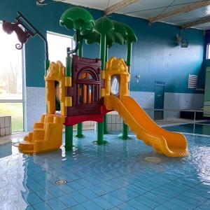 un parque infantil con tobogán en una piscina en cottage chaleureux dans domaine privé, en Signy-le-Petit