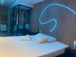 Schlafzimmer mit einem Bett mit Neonschild in der Unterkunft Up Motel in Ribeirão Preto