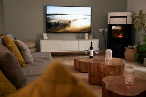 sala de estar con TV de pantalla plana en la pared en Tiny Whale Lodge, a unique space for groups, en Bensafrim
