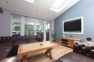 sala de estar con sofá y TV en Luxe Arthurs Seat View Townhouse with Hot Tub, en Edimburgo