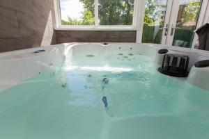a bath tub filled with blue water in a bathroom at Luxe Arthurs Seat View Townhouse with Hot Tub in Edinburgh