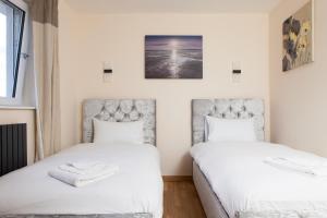 2 camas en una habitación con sábanas blancas en Luxe Arthurs Seat View Townhouse with Hot Tub, en Edimburgo