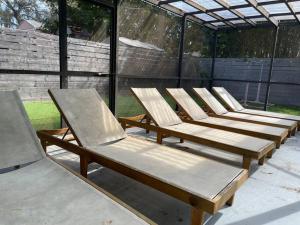 a row of wooden chaise lounges are lined up at Backyard oasis family fun! in St. Petersburg