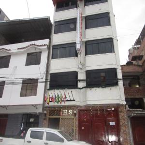 a white building with a white car parked in front of it at Gran Hostal Los Pinos in Cajamarca