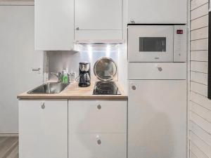 a white kitchen with a sink and a refrigerator at Holiday Home Rakkaranta b- lentäjän poika 2 by Interhome in Hyrynsalmi