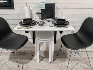 a white table with two chairs and a table with bowls of food at Holiday Home Rakkaranta b- lentäjän poika 2 by Interhome in Hyrynsalmi