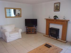 uma sala de estar com uma cadeira e uma lareira em Appartement du Pont neuf em Villegailhenc
