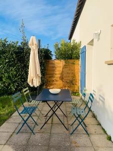 una mesa, sillas y una sombrilla en el patio en Bord de mer, maison paisible et rénovée à Penvins, en Sarzeau