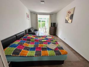 Zamárdi Parti Apartman في زاماردي: غرفة نوم مع سرير ولحاف ملون عليها