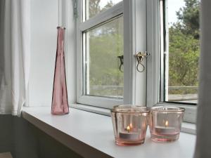 twee kaarsen op een vensterbank naast een raam bij Apartment Withar - all inclusive - 800m from the sea by Interhome in Fanø