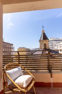 a wicker chair sitting on a balcony with a church at TrendyHomes San Sebastián in Almería