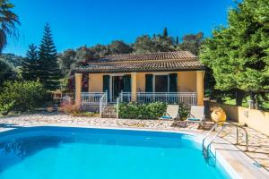 una villa con piscina di fronte a una casa di Villa Marias Beach House by Villa Plus ad Ágios Stéfanos