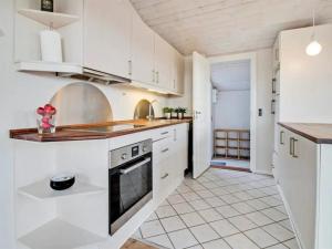 een keuken met witte kasten en een fornuis met oven bij Holiday Home Baarde - all inclusive - 60m from the sea by Interhome in Grenå