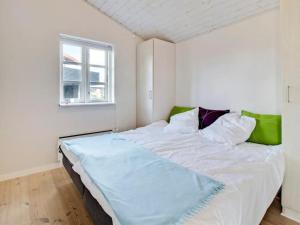 a large white bed in a room with a window at Holiday Home Baarde - all inclusive - 60m from the sea by Interhome in Grenå