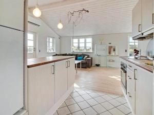 een keuken met witte kasten en een woonkamer bij Holiday Home Baarde - all inclusive - 60m from the sea by Interhome in Grenå