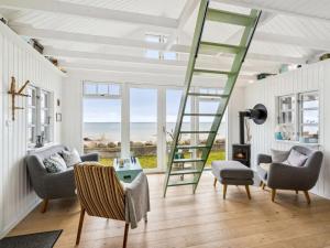 een woonkamer met een ladder, stoelen en een tafel bij Holiday Home Ofrath - all inclusive - 5m from the sea by Interhome in Otterup