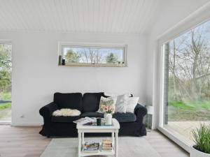 ein Wohnzimmer mit einem schwarzen Sofa und einem Tisch in der Unterkunft Holiday Home Sys - all inclusive - 150m from the sea by Interhome in Knebel