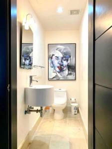 ein Badezimmer mit einem Waschbecken und einem WC mit Gemälden in der Unterkunft SUPER Spacious Modern Relax/CiPLA/CECiLIP in Santo Domingo