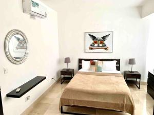 ein Schlafzimmer mit einem Bett mit 2 Tischen und einem Spiegel in der Unterkunft SUPER Spacious Modern Relax/CiPLA/CECiLIP in Santo Domingo