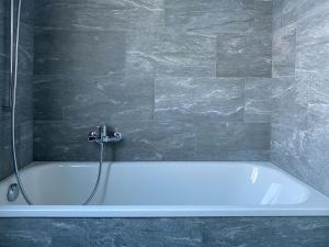 uma banheira branca na casa de banho com um chuveiro em Apartment Chalet Colette-2 by Interhome em Grindelwald