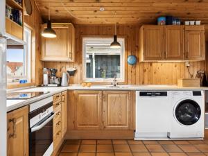 een keuken met houten kasten en een wasmachine en droger bij Holiday Home Dolores - all inclusive - 200m from the sea by Interhome in Torsted