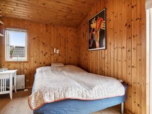 een slaapkamer met een bed in een kamer met houten wanden bij Holiday Home Dolores - all inclusive - 200m from the sea by Interhome in Torsted