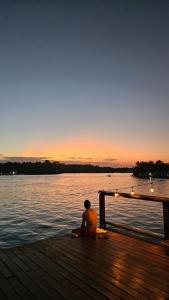 Ein Mann sitzt auf einem Dock und sieht den Sonnenuntergang. in der Unterkunft Hotel Blue Olas in Bocas del Toro