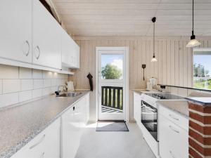 eine Küche mit weißen Schränken und eine Tür mit einem Fenster in der Unterkunft Holiday Home Griselda - all inclusive - 400m from the sea by Interhome in Hadsund