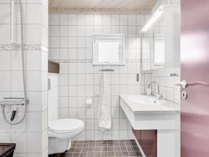 ein weißes Bad mit einem WC und einem Waschbecken in der Unterkunft Holiday Home Griselda - all inclusive - 400m from the sea by Interhome in Hadsund