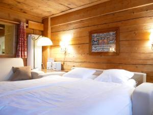 a bedroom with two white beds and a wooden wall at Apartment Les Moulins by Interhome in Verbier