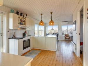 a kitchen with white cabinets and a wooden floor at Holiday Home Carstina - all inclusive - 400m from the sea by Interhome in Skagen