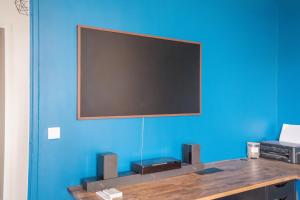 a flat screen tv on a blue wall at Le Contemporain ~ T4 Spacieux ~ RER A & Disney in Torcy