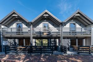 a house with tables and benches in front of it at Elmak Domki Całoroczne in Mikoszewo