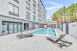 a swimming pool with two chairs next to a building at Wingate by Wyndham Tuscaloosa in Tuscaloosa