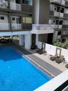 a swimming pool in front of a building with chairs at Condotel810byWVtowers1&2 in Iloilo City