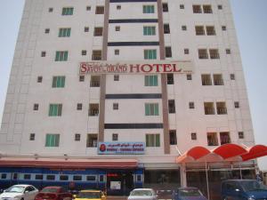 a hotel with cars parked in front of it at Savoy Grand Hotel Apartments in Muscat