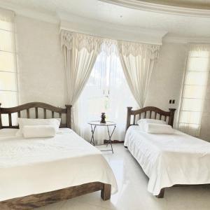 two beds in a white bedroom with a window at Casa Blanca in La Vega