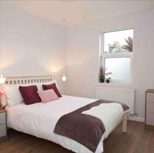 a bedroom with a white bed with pillows and a window at London 2 bed apartment in Woolwich