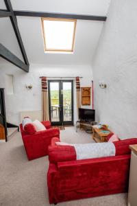 una sala de estar con 2 sofás rojos y una ventana en Treworgie Barton - Trespaddick, en Bude