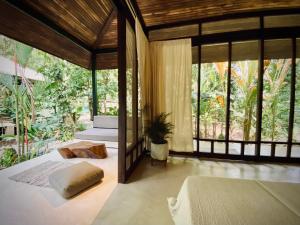 a bedroom with two beds and large windows at AIRE in Puerto Viejo