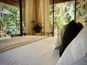 a bedroom with a large bed with a large window at AIRE in Puerto Viejo