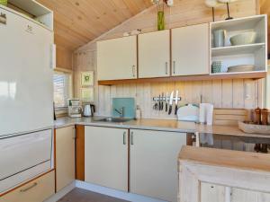 uma cozinha com armários brancos e um tecto de madeira em Holiday Home Kiana - all inclusive - 15m from the sea by Interhome em Hjørring