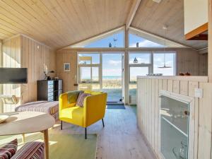 uma sala de estar com uma cadeira amarela e uma mesa em Holiday Home Kiana - all inclusive - 15m from the sea by Interhome em Hjørring