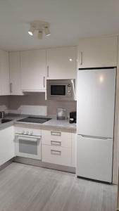 uma cozinha com armários brancos e um frigorífico branco em Apartamento moderno a 1km de Granada em Granada