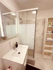 uma casa de banho branca com um lavatório e um chuveiro em Studio Élégant à Cergy em Cergy