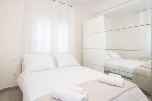 a white bedroom with two beds and a mirror at Zografou House Living in Athens