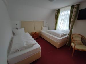 a bedroom with two beds and a chair and a window at Room in Guest room - Pension Forelle - double room in Forbach