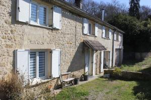 Cette ancienne maison en pierre est dotée de volets blancs et d'un banc. dans l'établissement Superbe maison dans un ancien moulin de lignan, à Lignan-de-Bordeaux