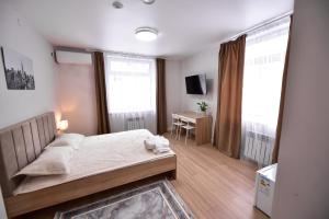 sypialnia z łóżkiem i biurkiem oraz 2 oknami w obiekcie SAFIA Hotel w mieście Pawłodar
