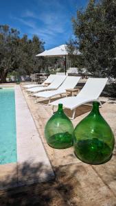 dos jarrones de cristal verde sentados junto a una piscina en Tenuta Lavati, Santa Maria di Leuca, en Castrignano del Capo